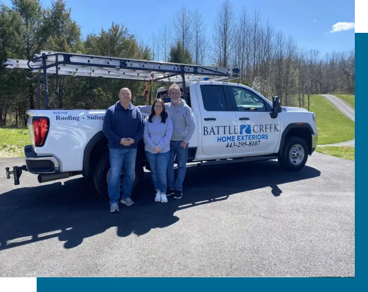Three people standing in front of a Battle Creek Plumbing truck outdoors.